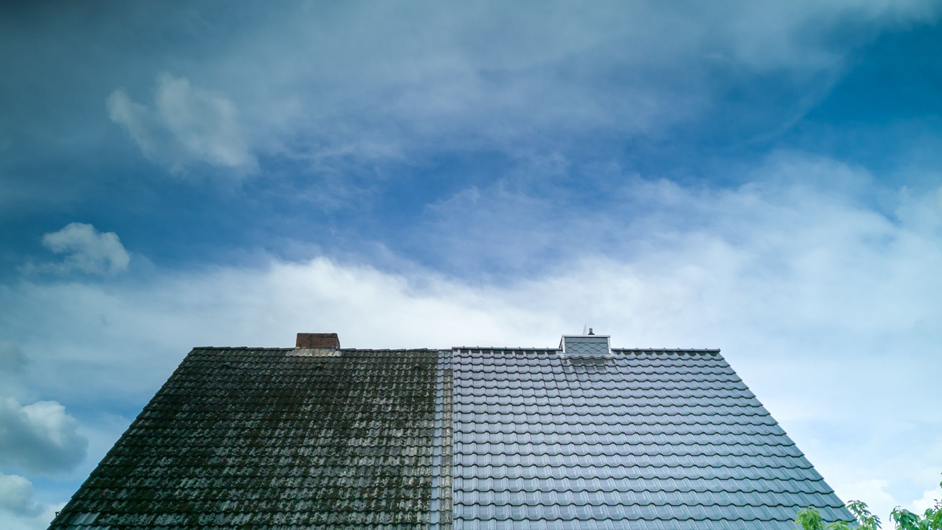 Tiled roof with two different shades against blue cloudy sky